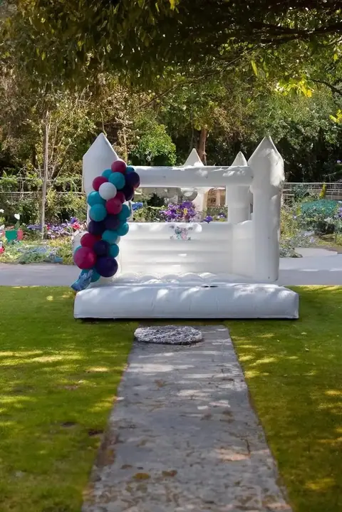 White bounce castle with a teal and navy balloon column