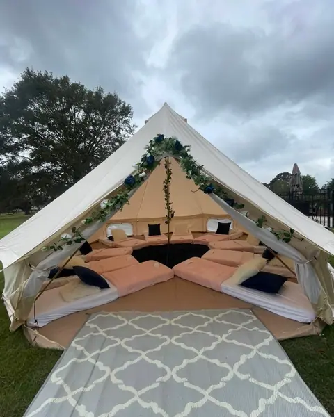 Open bell tent with floor beds and greenery garland