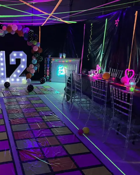 Glow party room lit in purple with a light-up number 12 and neon signs