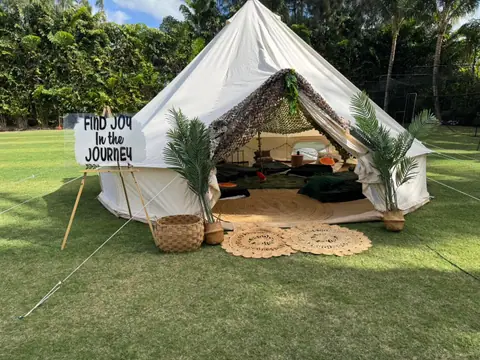 Styled glamping bell tent on the lawn with rugs and palms at the door