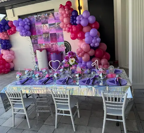 Pink and purple balloon garland over a styled birthday table