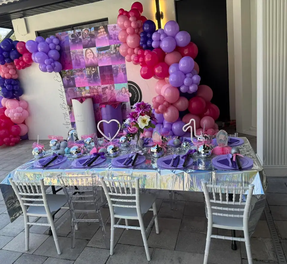 Pink and purple balloon garland over a styled birthday table