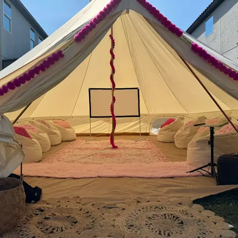 Inside a lit bell tent with bean bags and a movie screen
