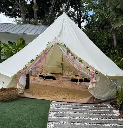 Bell tent with pink ribbons set up in a backyard