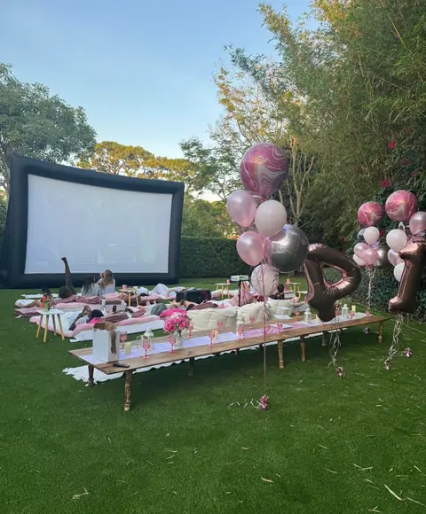 Garden picnic table and balloons in front of an outdoor movie screen