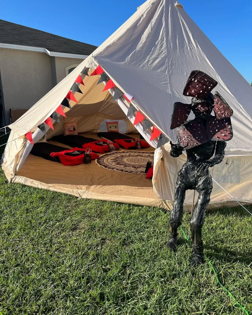 A man standing in front of a tent, immersed in glamping training videos.