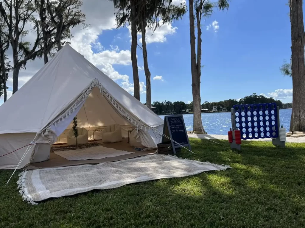 A white Ultimate Movie Night Setup Training Package - Transform Your Events set up in the grass next to a lake.