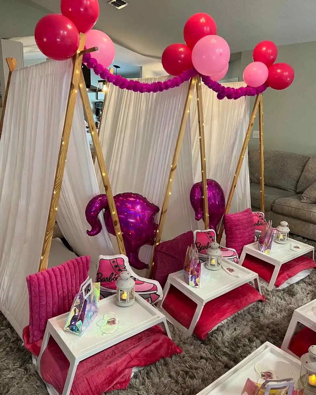 A pink and white party tent with balloons and decorations.